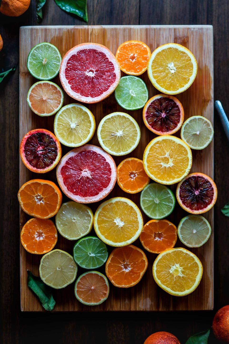 assorted sliced citrus fruits on brown wooden chopping board